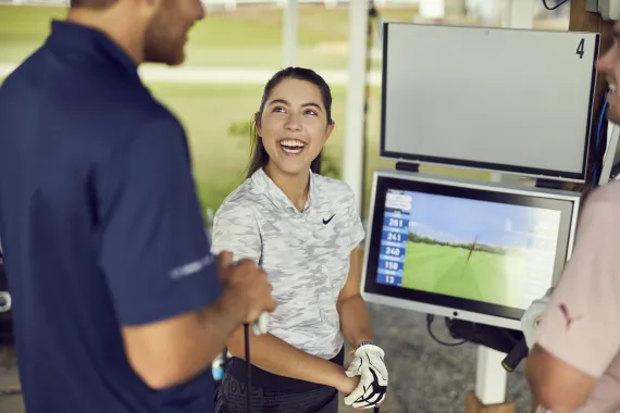 Image of a few people gathered around the screen smiling at their golf data