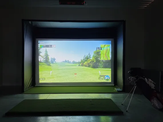 photo of the indoor simulator on and showing a golf course on the screen