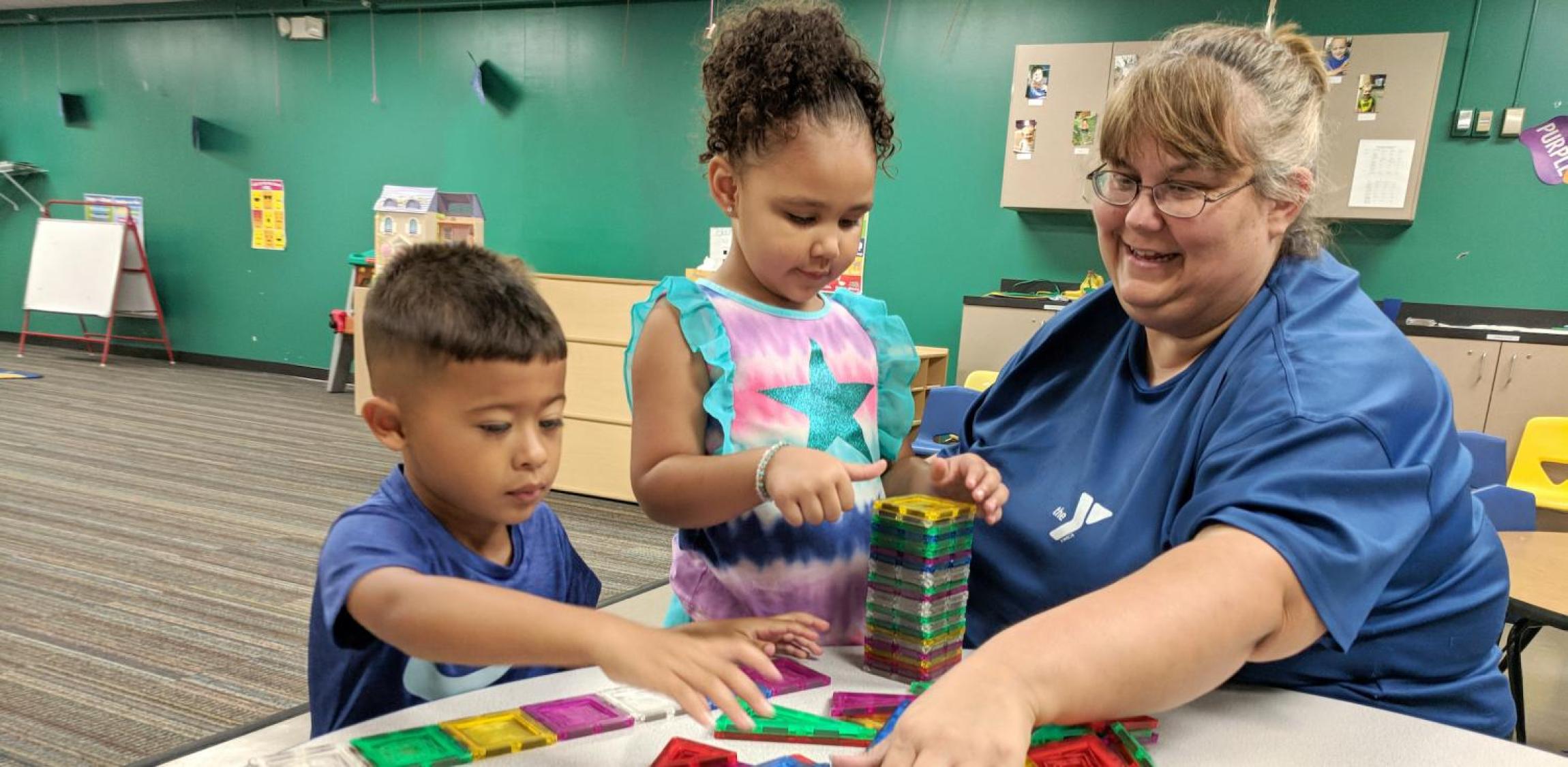 two young kids and teacher at preschool