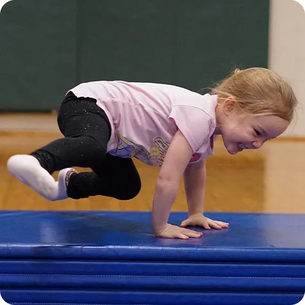 young girl tumbling on a mat